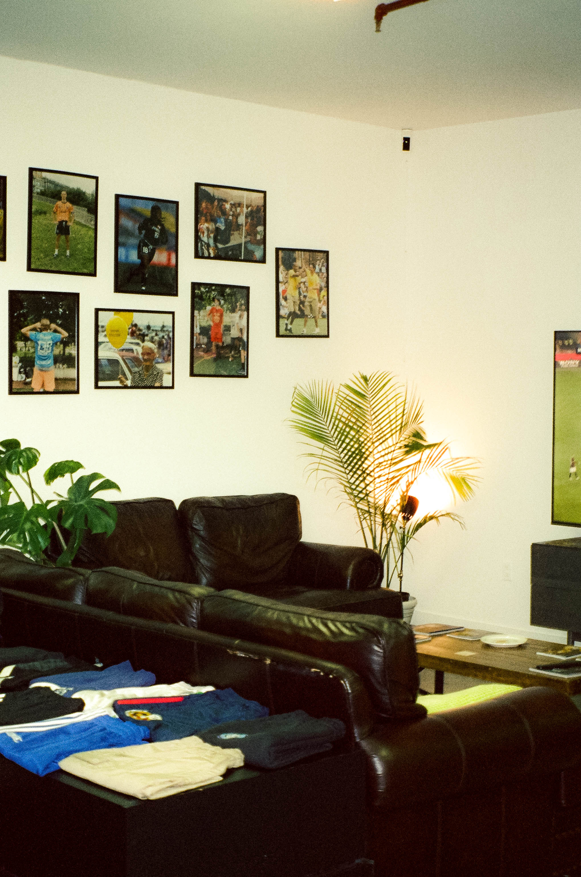 Framed football photographs above a leather sofa