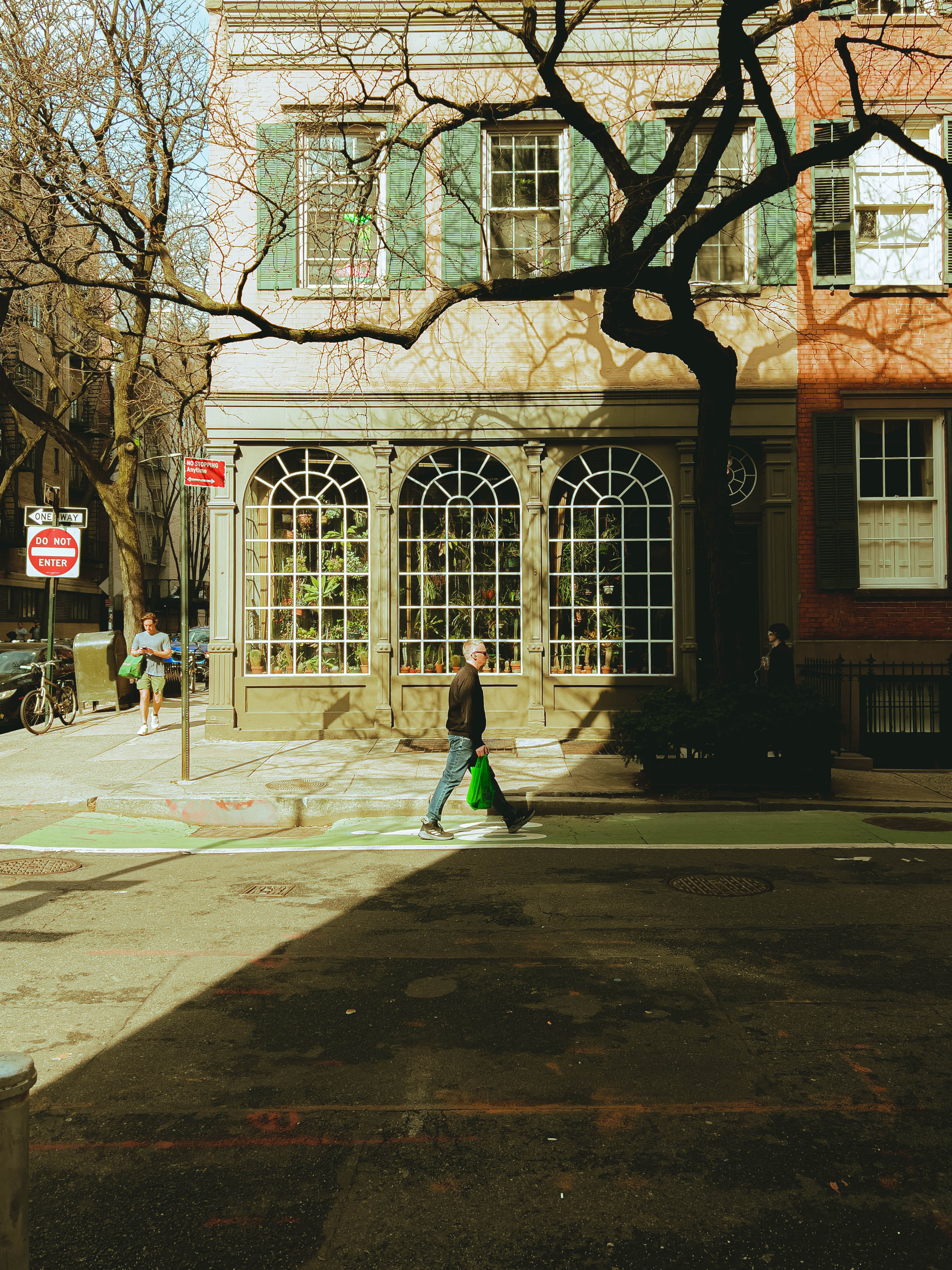 A pedestrian crossing a sunlit street